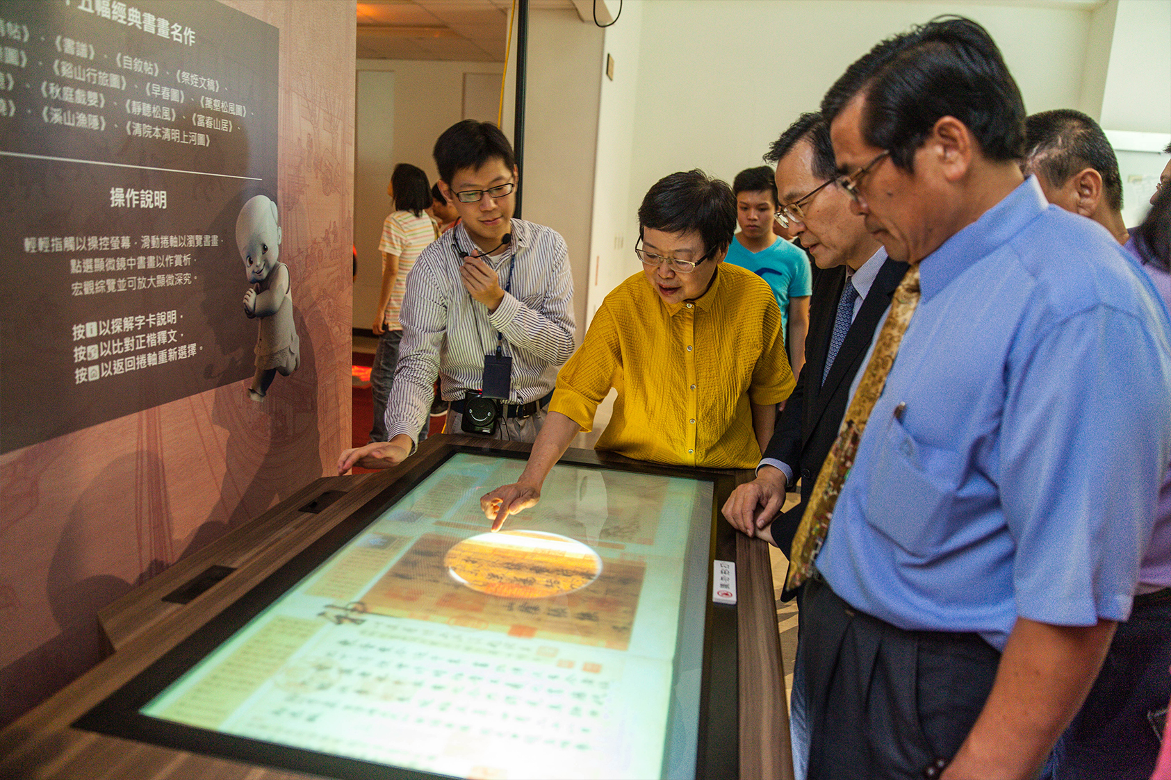 NPM Director Fung Mingchu demonstrates how to use the Must-See Interactive Tabletop to Taipower Company Chairman Huang Zhongqiu, et al.