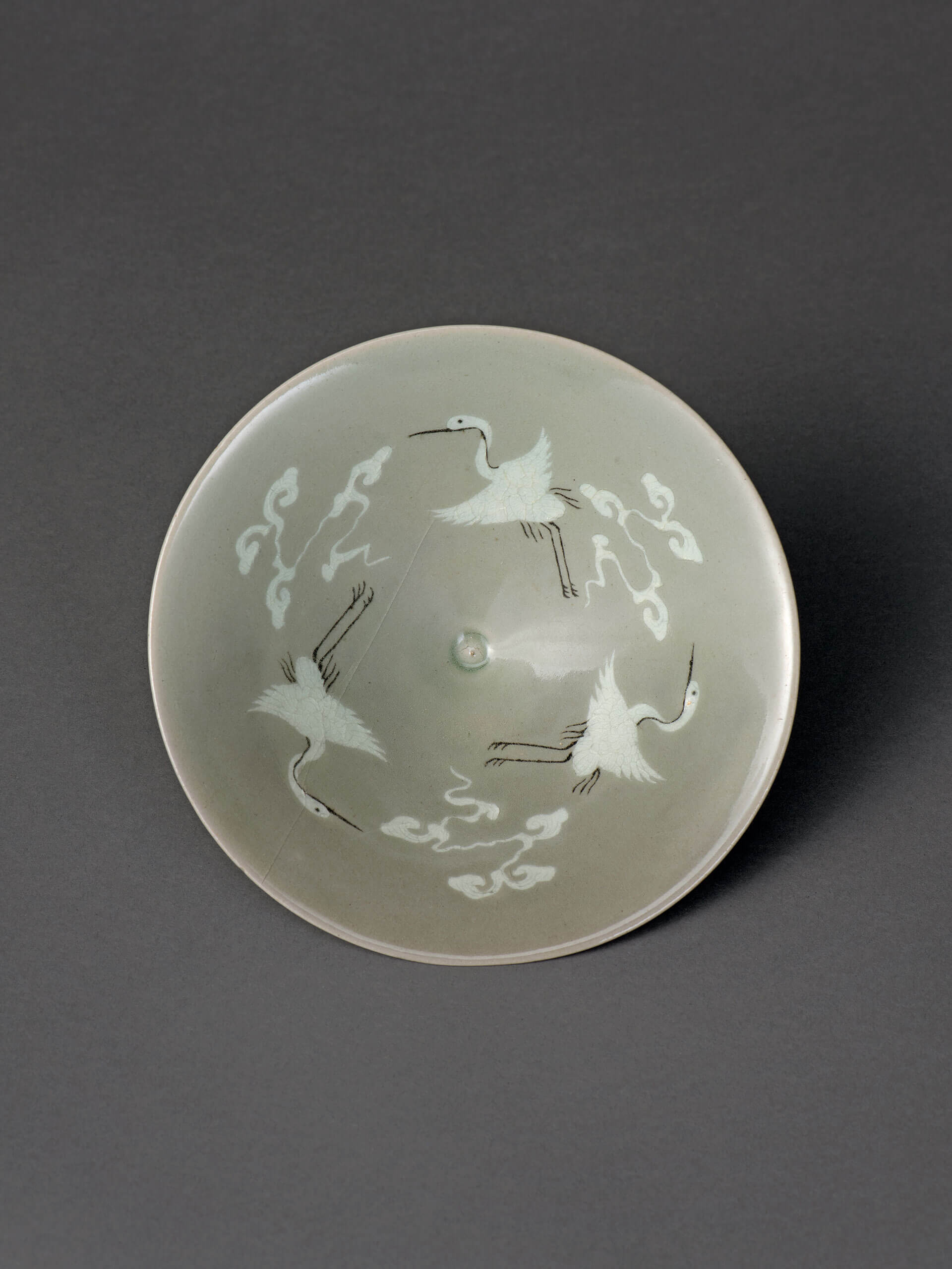 Bowl with inlaid cloud and crane design against celadon glaze