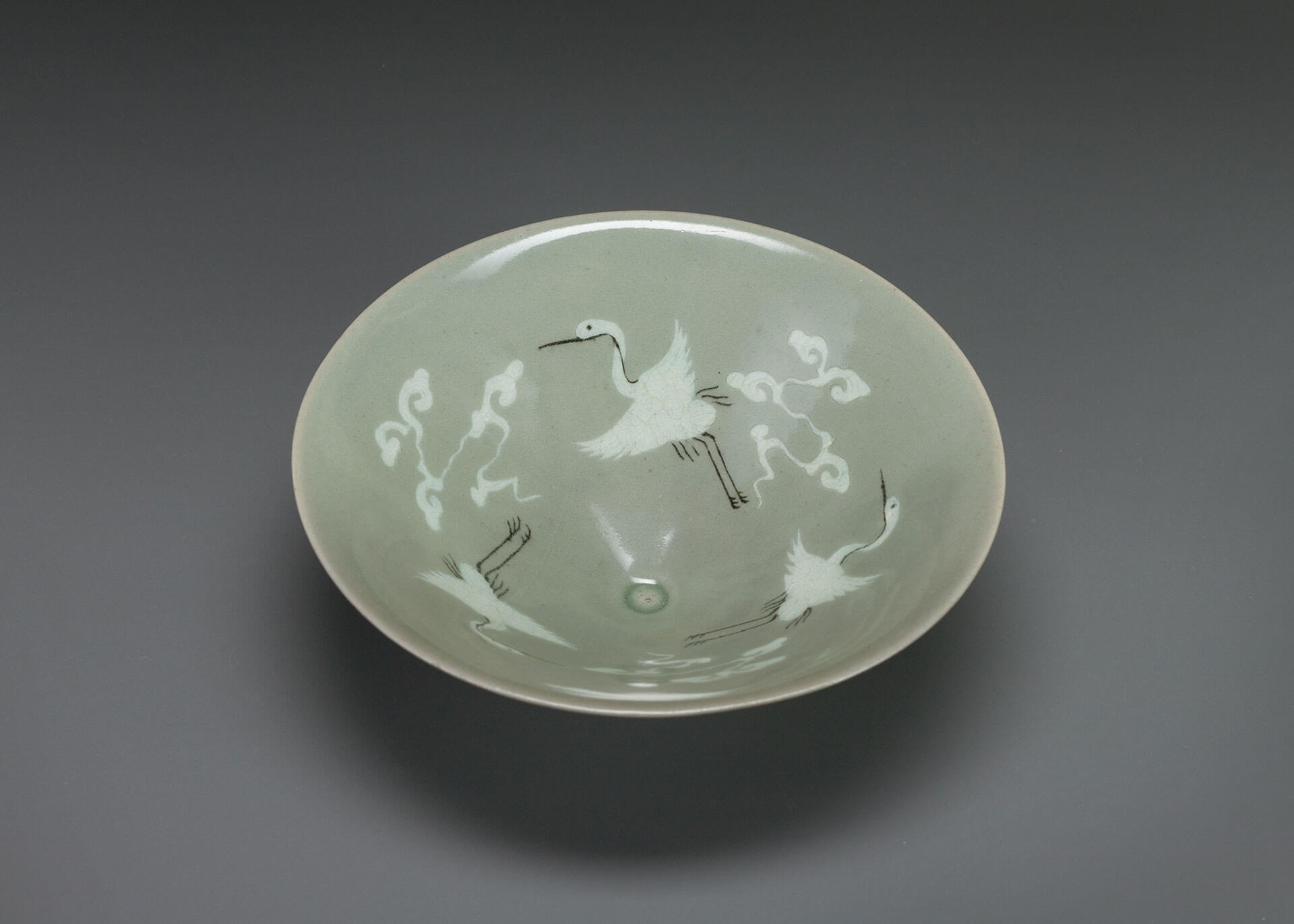 Bowl with inlaid cloud and crane design against celadon glaze